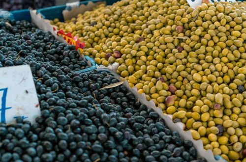 A vibrant selection of black and green olives at an outdoor market stall.