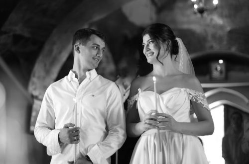 A bride and groom holding candles in a traditional romantic wedding ceremony setting.